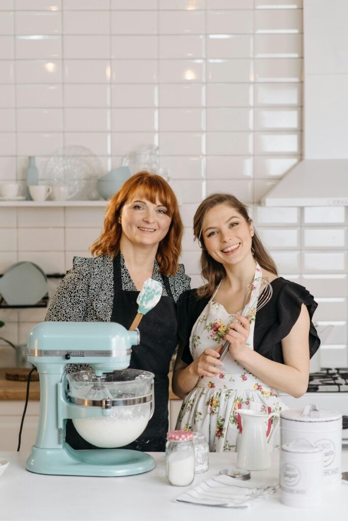 Smiling mother and daughter baking together in a modern kitchen.