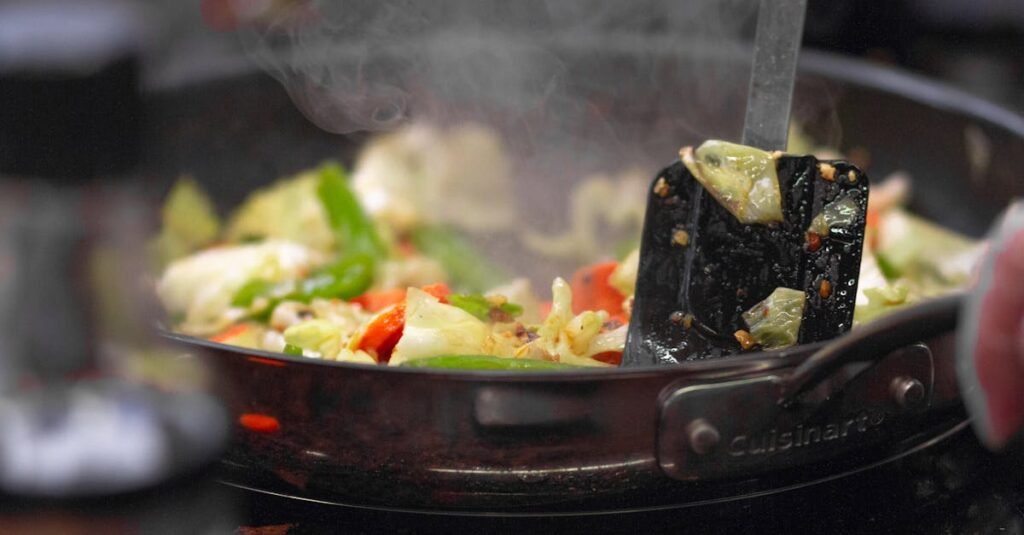 A vibrant stir fry of fresh vegetables sizzling in a pan, releasing steam.