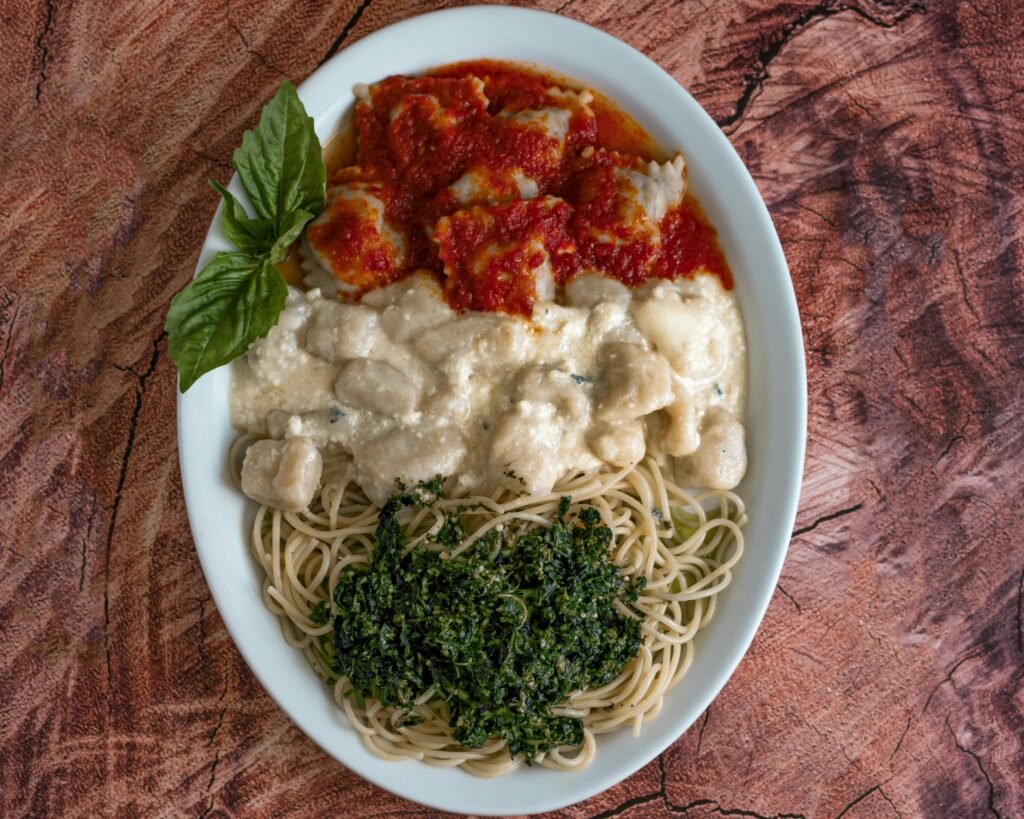 A top view of a plate with three varieties of Italian pasta served with fresh basil in Italy.