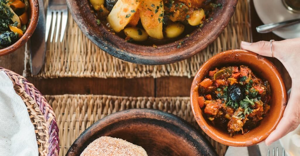 Delicious Moroccan dishes served with fresh vegetables and traditional bread on a woven mat.